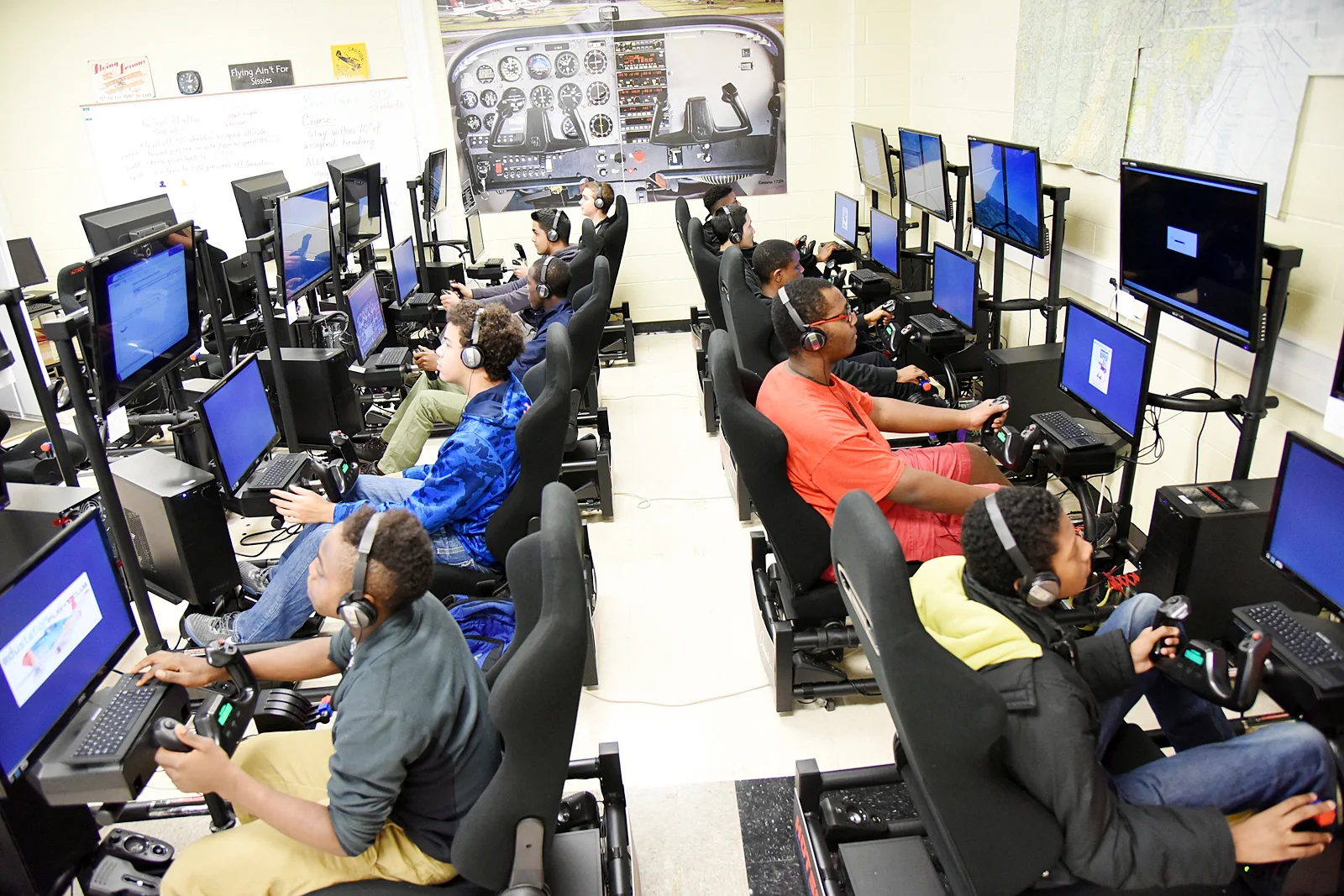 Students wearing headsets learn together on STEMPilot flight simulators